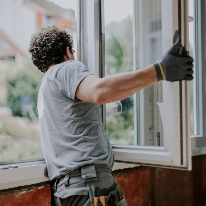Pose de Fenêtre : Installation et Rénovation par un Expert Poseur professionnel installant une fenêtre en PVC blanc lors d'une rénovation de maison.